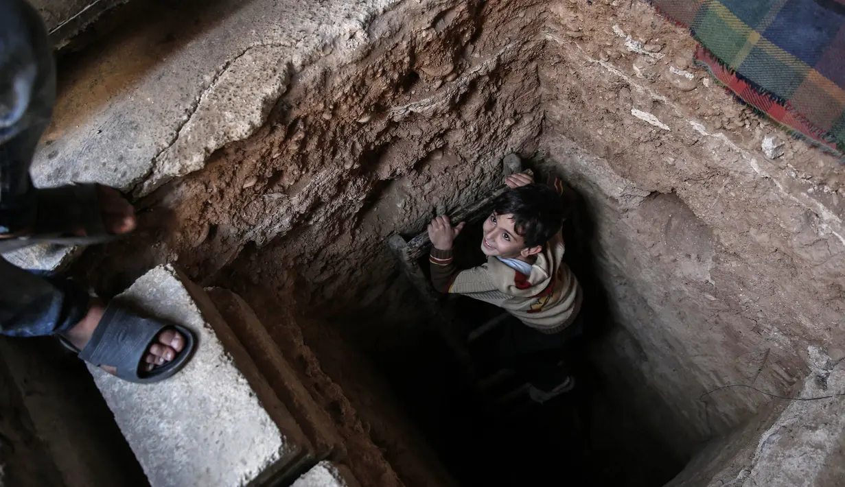 Seorang bocah berada di lubang menuju ruang bawah tanah Abu Omar di Douma, Damaskus, Suriah, (30/10). Abu Omar dibantu tetangganya berhasil menggali dan membangun ruangan di kedalaman 4 meter dari permukaan tanah. (AFP PHOTO/Sameer Al-Doumy)