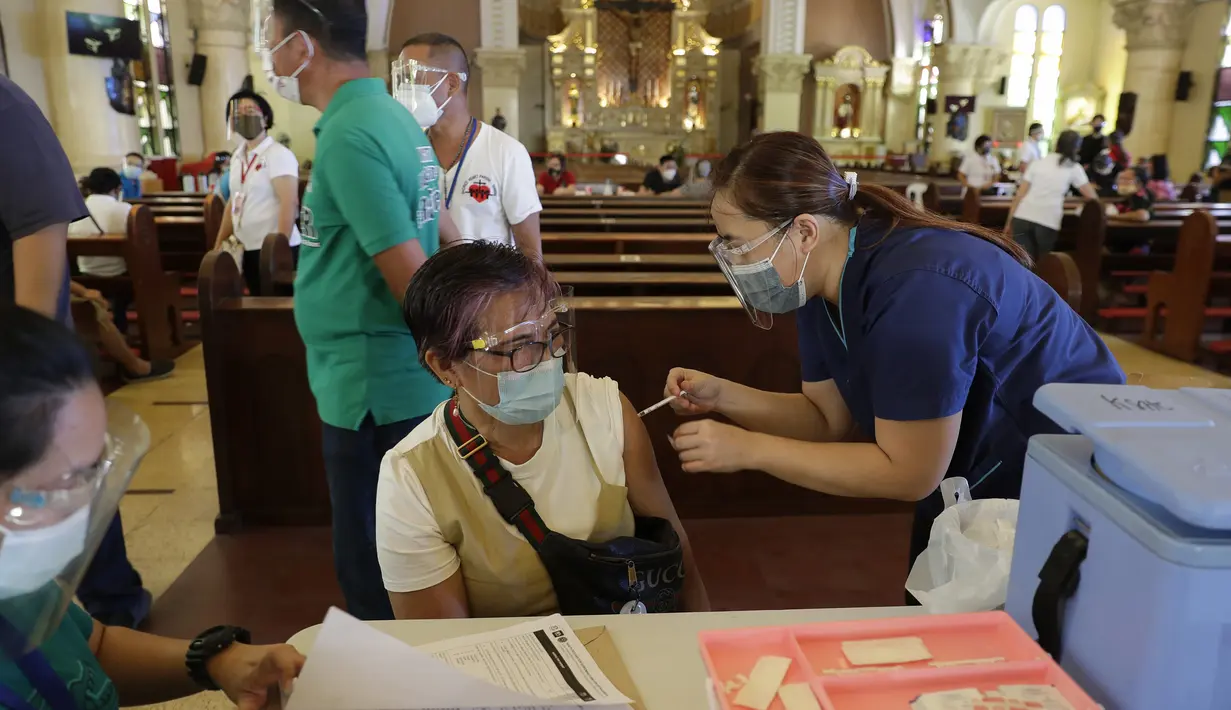 Petugas kesehatan menyuntik seorang perempuan dengan vaksin COVID-19 produksi AstraZeneca di dalam gereja Paroki Hati Kudus Yesus di Quezon City, Filipina, Senin (17/5/2021). Gereja itu digunakan untuk mempercepat proses vaksinasi kepada warga di daerah tersebut. (AP Photo/Aaron Favila)