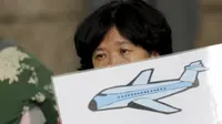 Salah satu keluarga penumpang MH370 membawa poster saat menggelar aksi di depan kantor Malaysia Airlines, Beijing, China, Kamis (6/8). Pemerintah Malaysia telah resmi menyatakan puing pesawat di Pulau Reunion adalah bagian dari MH370. (REUTERS/Jason Lee)