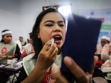 Seorang pengemudi ojek online wanita memoleskan lipstik saat kelas kecantikan jelang peragaan busana di Rawamangun, Jakarta, Jumat (20/4). Kegiatan digelar menyambut Hari Kartini yang jatuh pada 21 April mendatang. (Liputan6.com/Fery Pradolo)