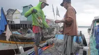 Para nelayan sedang memperbaiki gulungan jaring yang menggumpal. Agar bisa menggunakan jaring, para nelayan perlahan-lahan memperbaiki jaringnya
