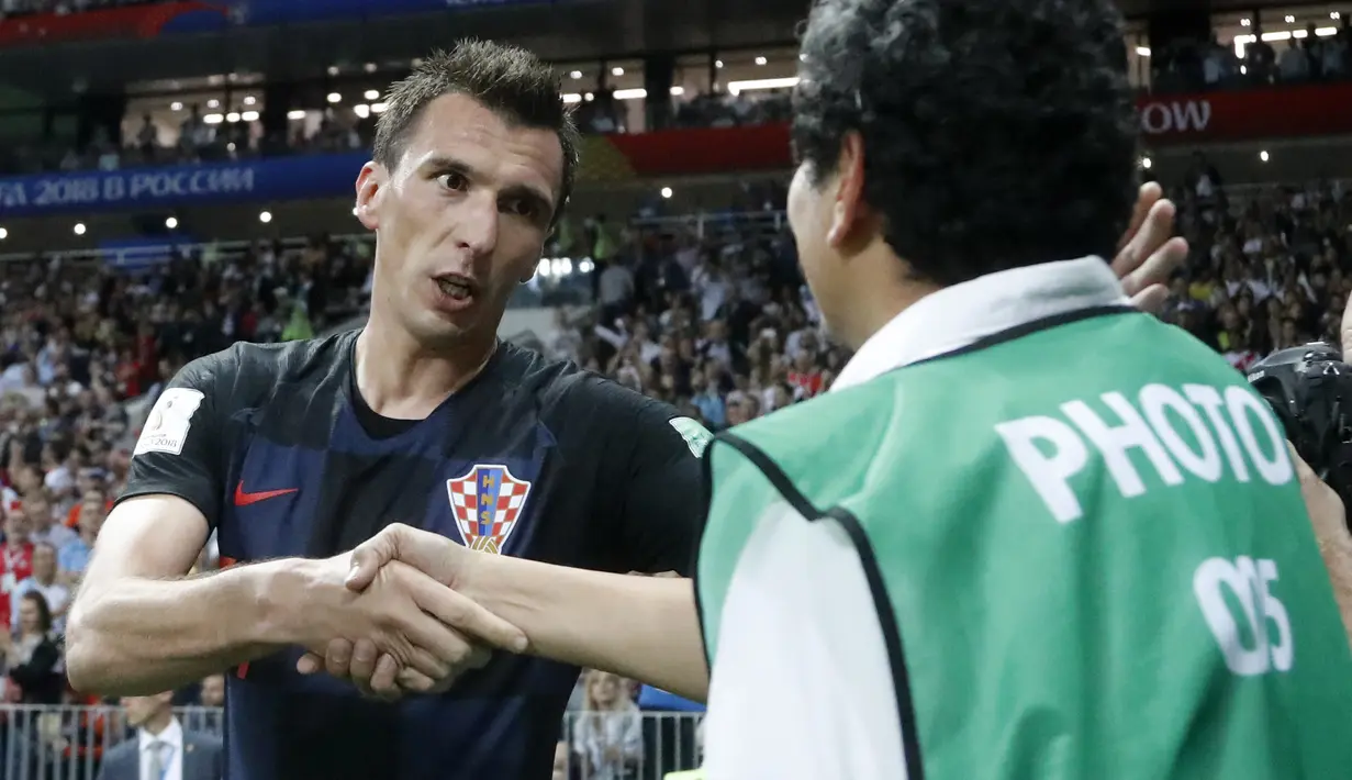 Mario Mandzukic meminta maaf dan bersalaman dengan Yuri Cortez usai merayakan gol ke gawang Inggris pada semifinal Piala Dunia 2018 di Luzhniki Stadium, Moskow, (11/7/2018). Yuri jatuh saat perayaan gol skuat Vatreni tersebut. (AP/Frank Augstein)