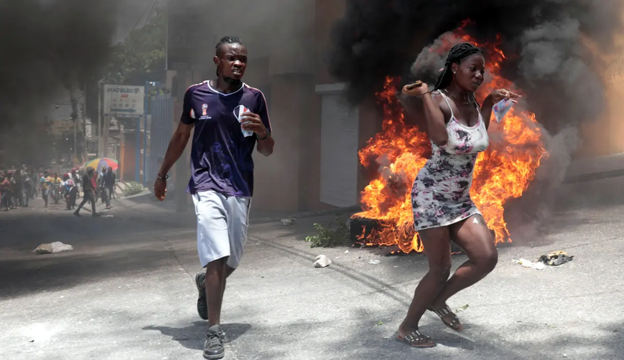 Demonstran berlari melewati ban yang dibakar selama protes terhadap ketidakamanan di Port-au-Prince, Haiti, Senin (7/8/2023). Ribuan warga Haiti turun ke jalan-jalan Port-au-Prince untuk memprotes kurangnya keamanan. (AP Photo/Odelyn Joseph)