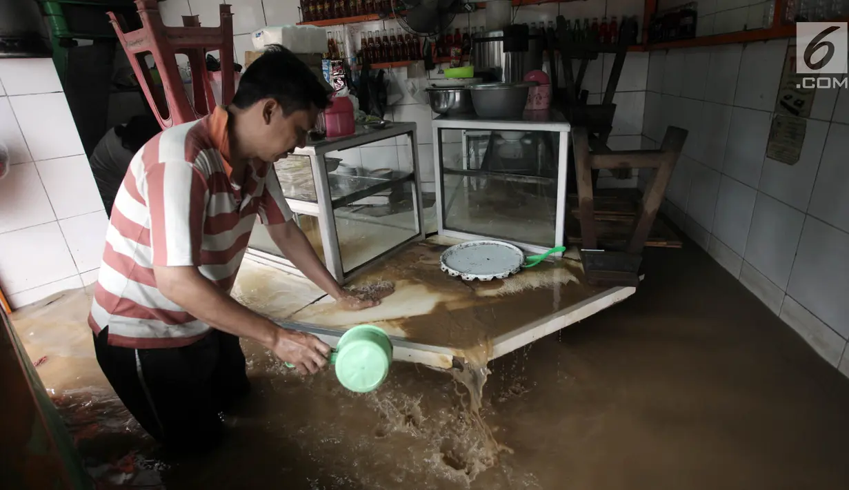Warga membersihkan meja makan dengan air saat banjir merendam Jalan Jatinegara Barat, Jakarta Timur, Selasa (6/2). (Liputan6.com/Arya Manggala)