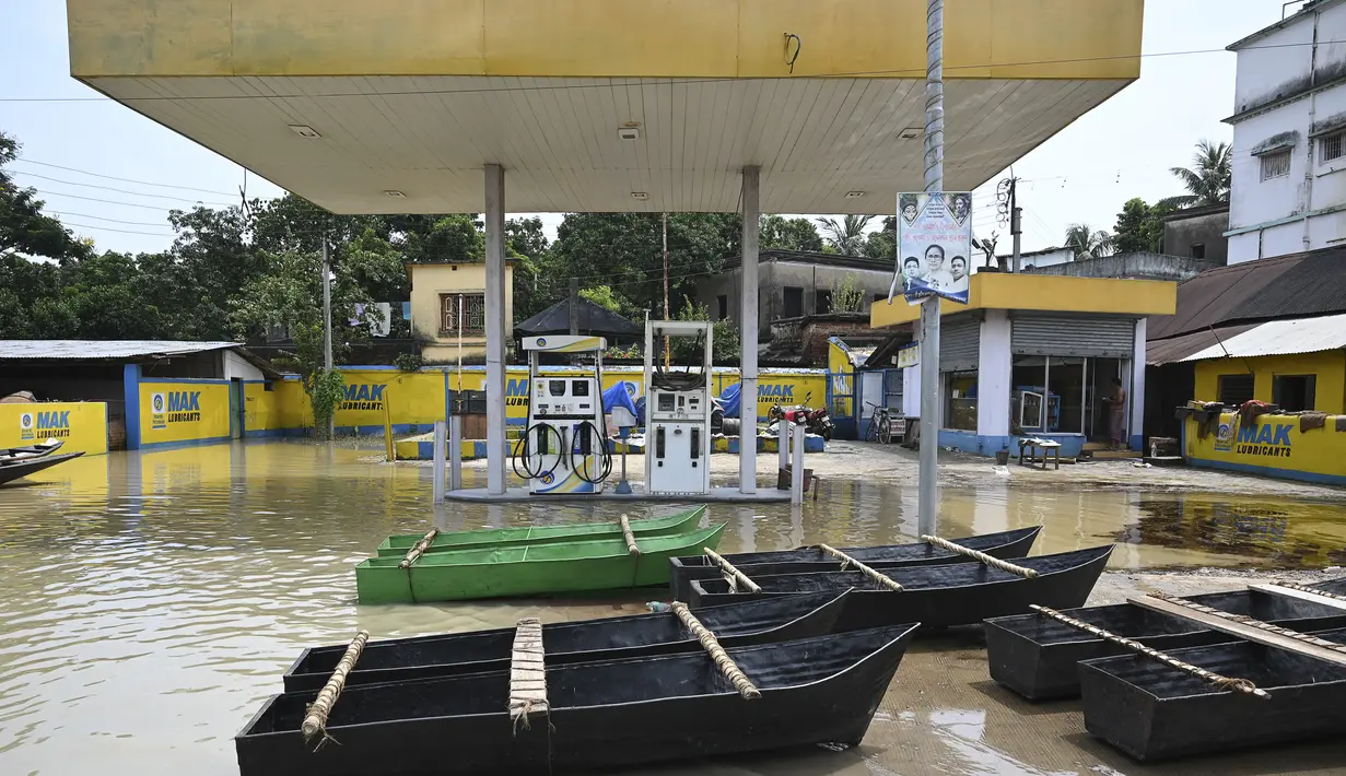 Perahu warga tampak terparkir di stasiun pengisian bahan bakar yang terendam banjir di Ghatal, distrik Paschim Medinipur, sekitar 100 km dari Kolkata (2/8/2021). Banjir parah akibat hujan lebat membuat jalanan di Ghatal berubah bak sungai. (AFP/Dibyangshu Sarkar)