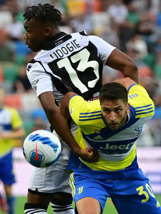 Pemain Udinese Destiny Udogie (kiri) berebut bola dengan pemain Juventus Rodrigo Bentancur pada pertandingan Liga Italia Serie A di Dacia Arena Stadium, Udine, Italia, 22 Agustus 2021. Pertandingan berakhir dengan skor 2-2. (MIGUEL MEDINA/AFP)
