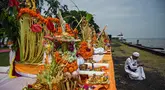 Seorang umat Hindu mempersiapkan persembahan untuk sembahyang selama upacara ritual Melasti di Pantai Arafuru, Surabaya, 23 Maret 2025. (JUNI KRISWANTO/AFP)