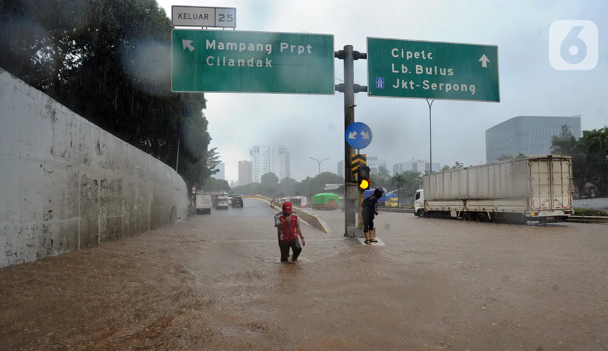 Seorang pria menyusuri banjir yang menggenangi Jalan Tol JORR di kawasan TB Simatupang, Jakarta Selatan, Sabtu (20/2/2021). Banjir terjadi akibat luapan Kali Serua yang berada di pinggir jalan tol. (merdeka.com/Arie Basuki)