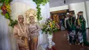 Sejumlah pasangan pengantin antre untuk foto saat mengikuti nikah massal di Surabaya, Jawa Timur, Rabu (18/12/2019). Sebanyak 60 pasangan pengantin mengikuti nikah massal yang digelar Dinas Sosial Kota Surabaya. (JUNI KRISWANTO/AFP)