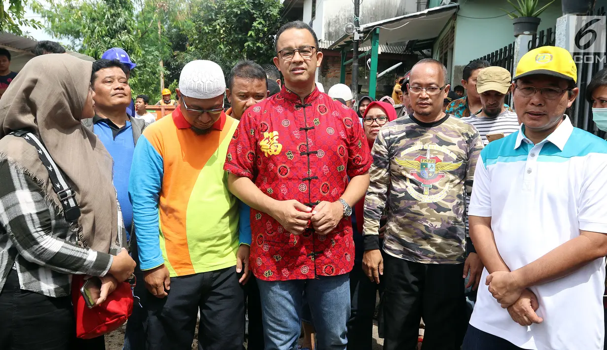 Gubernur DKI Anies Baswesdan meninjau lokasi jalan retak di  Kelurahan Kebon Manggis, Kecamatan Matraman, Jakarta Timur, Jumat (16/2). Kehadiran Anies yang mengenakan baju tradisional China itu mengundang perhatian warga sekitar (Liputan6.com/Johan Tallo)