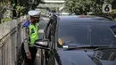 Polisi lalu lintas berkomunikasi dengan pengendara mobil saat Operasi Zebra Jaya 2022 di Jakarta, Selasa (4/10/2022). Operasi Zebra Jaya dilaksanakan pada tanggal 3 hingga 17 Oktober untuk menekan jumlah pelanggaran lalu lintas. (Liputan6.com/Faizal Fanani)