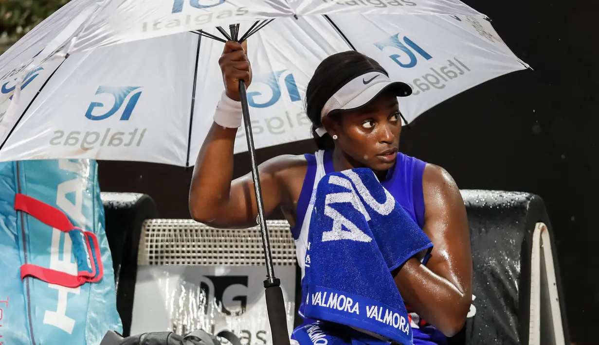 Petenis Amerika Serikat, Sloane Stephens, memegang payungnya sendiri saat diguyur hujan pada laga Italian Open 2020 di Foro Italico, Selasa (15/9/2020). (AFP/Clive Brunskill/pool)