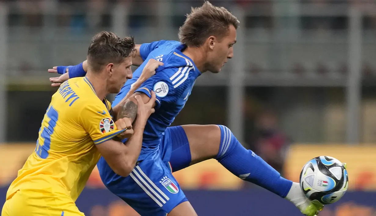 Striker Timnas Italia, Mateo Retegui (kanan) mengontrol bola dibayangi bek Timnas Ukraina, Illia Zabarnyi pada laga Grup C Kualifikasi Euro 2024 di San Siro Stadium, Milan, Rabu (13/9/2023) dini hari WIB. (AP Photo/Antonio Calanni)