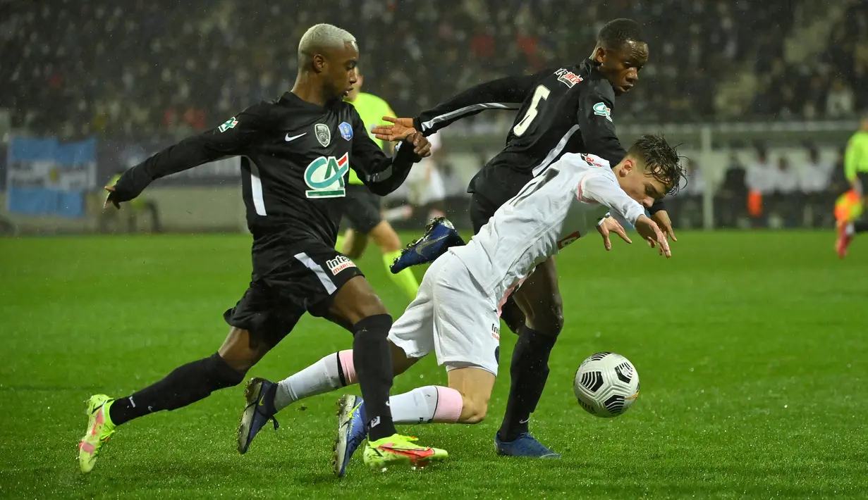 Bek Paris Saint-Germain (PSG) Edouard Michut (kanan) berebut bola dengan gelandang klub divisi empat, Vannes OC, Beninese Seibou Mama dalam babak 32 besar Piala Prancis di Stade de la Rabine, Selasa (4/1/2021) dini hari WIB. PSG menang 4-0 lewat hattrick Kylian Mbappe. (LOIC VENANCE/AFP)