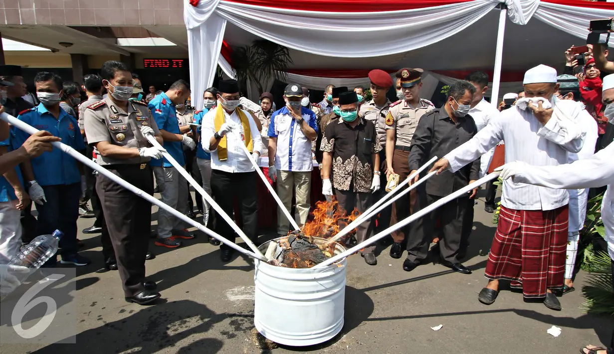 Tim dari Polres Metro Jakarta Selatan memusnahkan belasan ribu botol minuman keras berbagai merek dan belasan ribu gram ganja kering siap edar di halaman Mapolres Metro Jakarta Selatan, Kamis (2/6). (Liputan6.com/Immanuel Antonius) halaman 