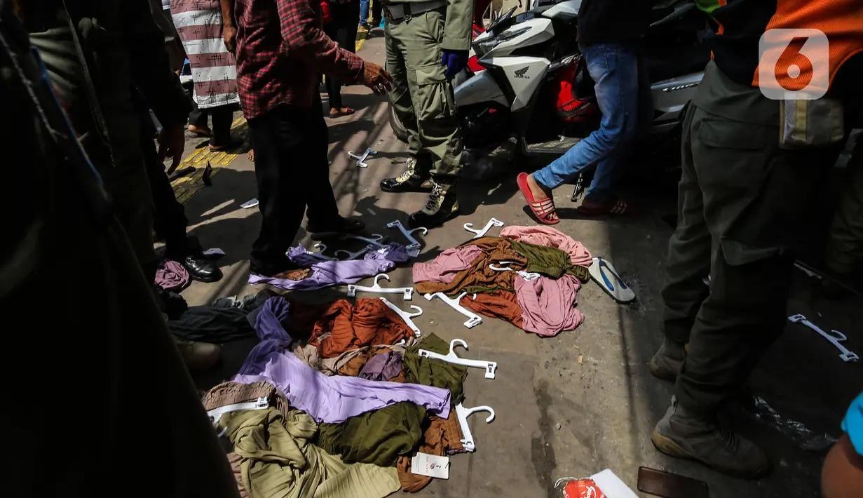 Sejumlah pakaian tergeletak saat aparat gabungan melakukan penertiban kepada pedagang yang berjualan di trotoar di kawasan Tanah Abang, Jakarta, Minggu (2/5/2021). Selain merazia barang dagangan pedagang, petugas juga menegur warga yang tidak menerapkan protokol kesehatan. (Liputan6.com/Johan Tallo)