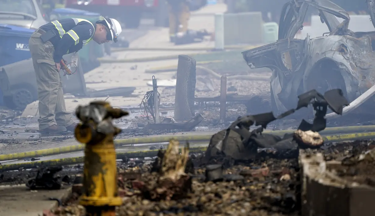 Petugas pemadam kebakaran memeriksa lokasi jatuhnya sebuah pesawat kecil jatuh di Santee, California, Senin (11/10/2021). Pesawat itu mengalami masalah dan mencoba mendarat di Gillespie Field—yang berada di dekat sebuah sekolah menengah, ketika jatuh. (AP Photo/Gregory Bull)