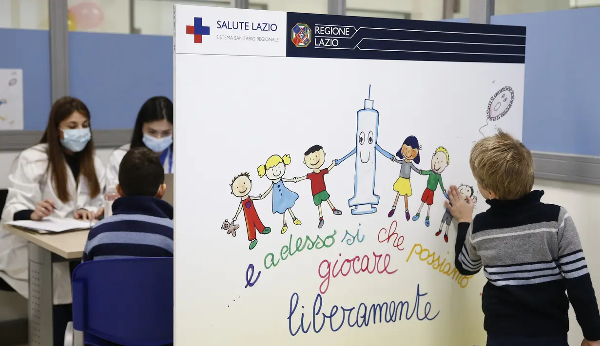 Seorang anak menyentuh poster kampanye vaksinasi COVID-19 untuk anak usia 5 - 11 tahun, di pusat vaksinasi di Roma, Rabu (16/12/2201). Italia mulai memvaksinasi anak-anak berusia 5-11 tahun saat pemerintah bersiap menghadapi penyebaran omicron selama musim liburan. (Cecilia Fabiano/LaPresse via AP)