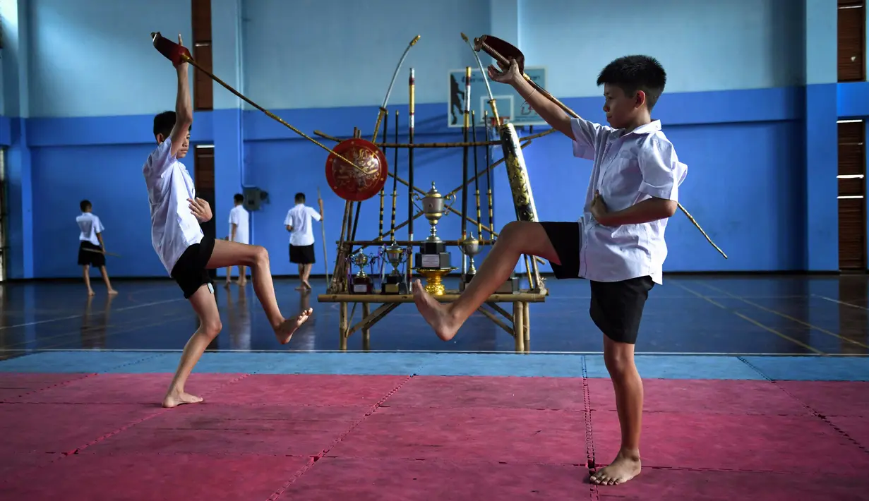 Dua siswa menggunakan pedang berlatih Krabi Krabong di sekolah Thonburee Woratapeepalarak, Thonburi, Bangkok (8/7/2019). Krabi Krabong merupakan seni bela diri Thailand yang dipersenjatai pisau dan perisai kayu yang terabaikan. (AFP Photo/Lillian Suwanrumpha)