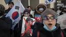 Pengunjuk rasa anti-Korea Utara membawa poster Kim Jong-Un saat menggelar aksi di pelabuhan Mukho di Donghae, Korea Selatan (6/2). Sekitar 120 seniman dari Korut akan tampil di Olimpiade Musim Dingin Pyeongchang 2018. (AFP/Ed Jones)