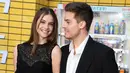 <p>Aktor Dylan Sprouse (kanan) dan model Barbara Palvin menghadiri pemutaran perdana film Bullet Train di Regency Village Theatre, Los Angeles, California, Amerika Serikat, 1 Agustus 2022. Sprouse tampil di karpet merah dengan kemeja putih yang sedikit terbuka tanpa dasi di dalam balutan jas hitam klasik. (Jon Kopaloff/Getty Images/AFP)</p>
