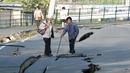 Penduduk setempat melihat jalan yang terbelah dua akibat gempa bumi yang menghantam kota Mashiki, Prefektur Kumamoto, Jepang selatan, Sabtu (16/4). Gempa berkekuatan 6,4 SR itu menewaskan sembilan orang dan 760 lainnya terluka. (REUTERS/Kyodo)