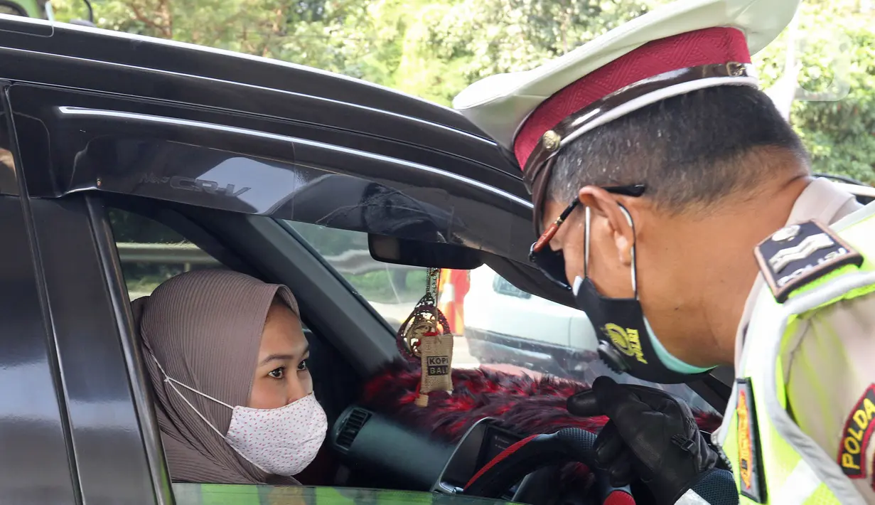 Petugas kepolisian berbincang dengan pengendara di pos penyekatan pemudik Tol Cikarang Barat, Kabupaten Bekasi, Jawa Barat, Minggu (9/5/2021).Petugas gabungan memperketat pemeriksaan dokumen kendaraan yang melintasi pos penyekatan pemudik jelang H-3  Idul Fitri 1442 H. (Liputan6.com/Herman Zakharia)