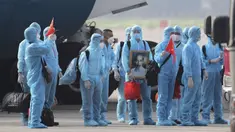 Pasien COVID-19 asal Vietnam mengenakan alat pelindung diri saat tiba di Bandara Noi Bai, Hanoi, Vietnam, Rabu (29/7/2020). Sebanyak 129 pekerja asal Vietnam dipulangkan dari Equatorial Guinea untuk mendapat perawatan COVID-19. (Tran Huy Hung/VNA via AP)
