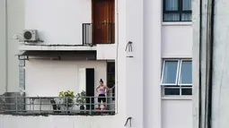 Gambar pada 4 September 2021 menunjukkan seorang perempuan berolahraga di balkon rumahnya di Hanoi, Vietnam, selama lockdown Covid-19. Menghadap ke jalan yang sepi, balkon kecil mereka menjadi saksi bisu terkait aktivitas yang dilakukan oleh masing-masing keluarga. (Nhac NGUYEN/AFP)