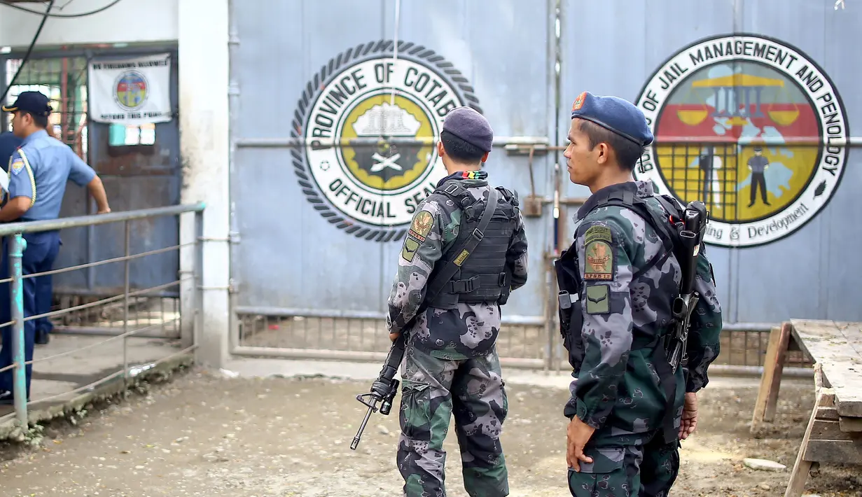 Polisi bersenjata lengkap berjaga di depan gerbang sebuah penjara di kota Kidapawan, selatan Filipina, Rabu (4/1). Sekelompok pria bersenjata dilaporkan menembus masuk penjara itu dan berhasil membebaskan lebih dari 150 tahanan. (Ferdinandh CABRERA/AFP)