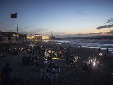 Orang-orang berbuka puasa di tepi pantai di Rabat, Maroko, Sabtu (23/4/2022). Untuk pertama kalinya dalam dua tahun sejak pandemi COVID-19, orang-orang dapat menghidupkan kembali tradisi Ramadhan dengan berkumpul dan berbuka puasa di tempat umum. (AP Photo/Mosa'ab Elshamy)