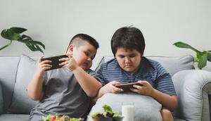 bermain game atau menonton video di gadget dengan posisi duduk terlalu lama di dalam posisi yang sama ditambah makanan yang memanjakan lidah, tentu dapat mengakibatkan obesitas pada anak. (Foto dok: Freepik/wasant_foodtography).