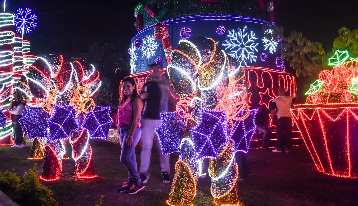 Pengunjung berpose di samping dekorasi Natal di Medellin, Kolombia (4/12). (AFP Photo/Joaquin Sarmiento)