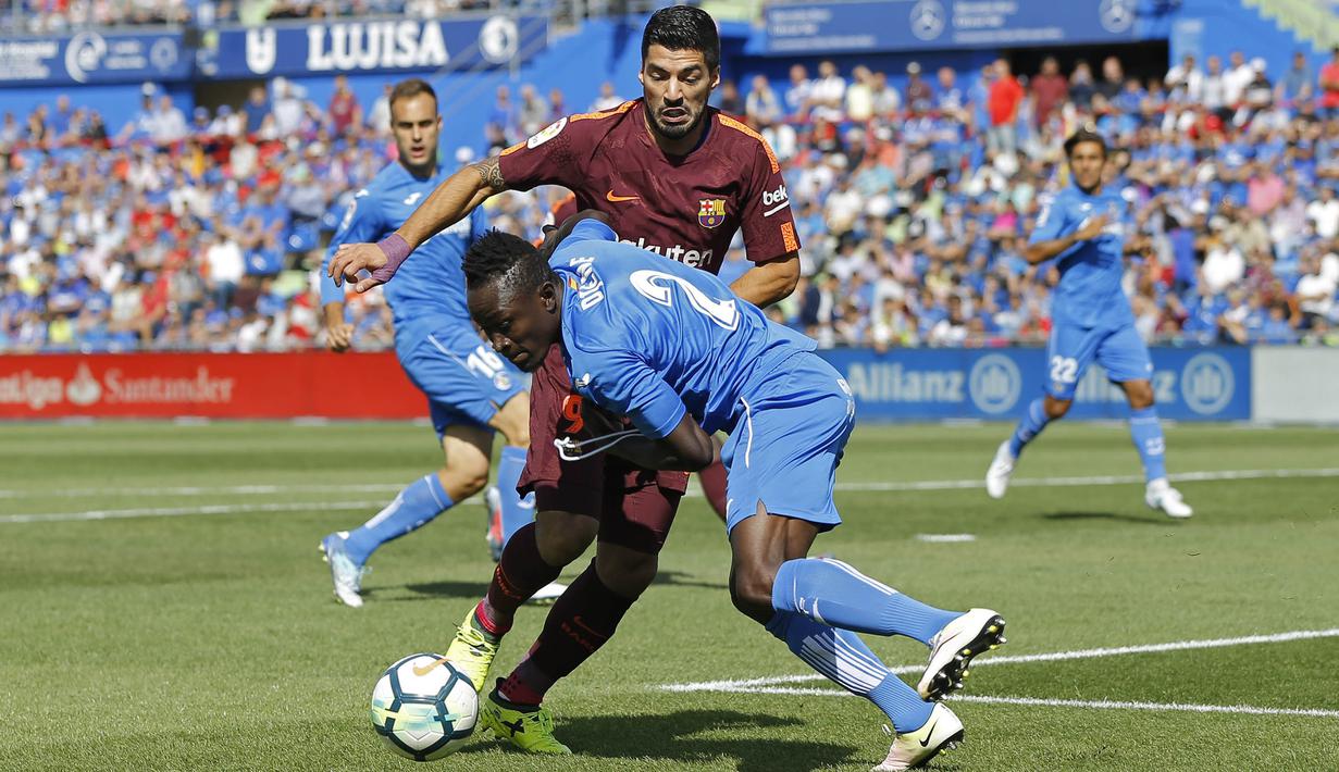 Striker Barcelona, Luis Suarez, berusaha melewati bek Getafe, Dakonam Djene, pada laga La Liga di Stadion Alfonso Perez, Sabtu (16/9/2017). Barcelona menang 2-1 atas Getafe. (AP/Francisco Seco)