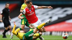 Gelandang Arsenal, Granit Xhaka, berebut bola dengan gelandang Norwich City, Tom Trybull, pada laga lanjutan Premier League pekan ke-32 di Emirates Stadium, Kamis (2/7/2020) dini hari WIB. Arsenal menang 4-0 atas Norwich City. (AFP/Shaun Botteril/pool)