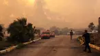 Warga dan petugas pemadam kebakaran berusaha memadamkan api saat asap dan kobaran api membumbung tinggi dari sebuah kawasan hutan menyusul kebakaran hutan di distrik Seferihisar, Izmir, Turki, pada 30 Juni 2025. (Ahmet Ayberk Cimen/AFP)