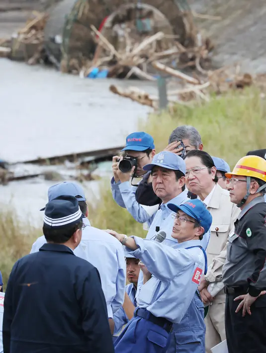 PM Jepang Shinzo Abe memeriksa daerah yang terkena dampak banjir dan longsor di Hita, prefektur Oita, Rabu (12/7). Meningkatnya jumlah korban akibat banjir memicu Abe yang tengah mengunjungi Eropa untuk segera kembali ke Negeri Sakura (STR/JIJI PRESS/AFP)