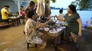 Pelanggan menyantap makanan di tengah banjir yang merendam Chaopraya Antique Café di Sungai Chao Phraya, Bangkok, Thailand, Kamis (7/10/2021). Restoran yang dilanda banjir ini menjadi tempat makan tidak biasa di mana pengunjung menikmati santapan makanan dengan kaki terendam (AP Photo/Sakchai Lalit)