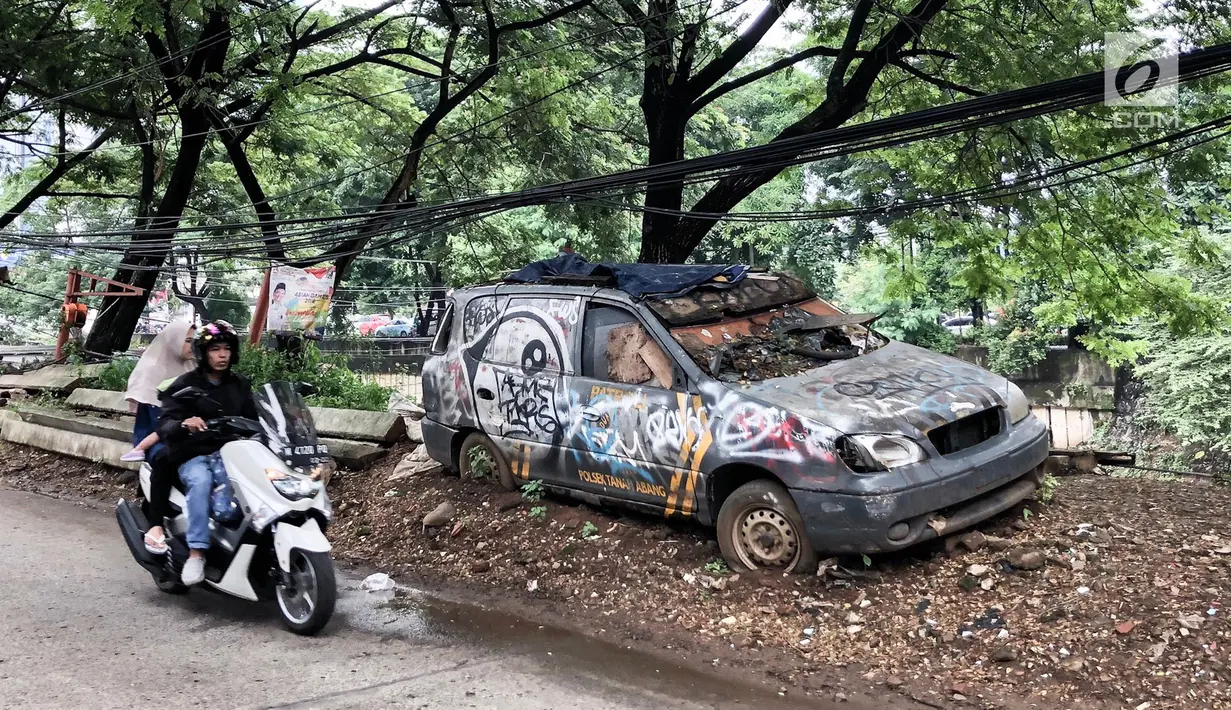 Pengendara motor melintas disamping sebuah mobil patroli Polsek Tanah Abang, Jakarta, Rabu (6/3). Mobil operasional merk KIA berkarat dan tidak tertutup terpal. (Liputan6.com/Fery Pradolo)