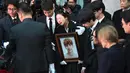 Kakak Jonghyun menangis dalam pelukan Minho SHINee saat peti jenazah dimasukkan ke mobil menuju tempat pemakaman dari rumah persemayaman di Asan Hospital, Seoul, Kamis (21/12). Kesedihan menyelimuti pelepasan peti jenazah Jonghyun. (JUNG Yeon-Je/AFP)