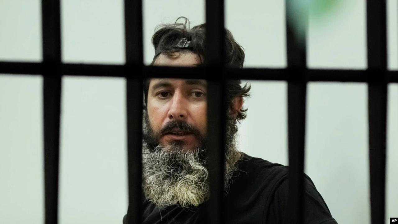 Bassam al-Sheikh Hussein (42), melihat melalui jendela bank, di Beirut, Lebanon, Kamis, 11 Agustus 2022. (AP/Hussein Malla)