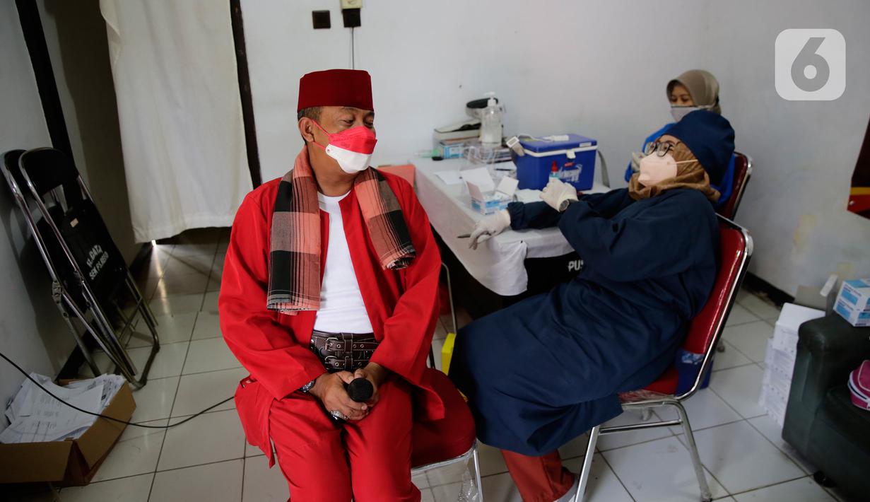 Petugas kepolisian berpakaian pejuang jaman berbincang dengan petugas medis saat vaksinasi Covid-19 di Polsek Pasar Rebo, Jakarta, Selasa (17/8/2021). Para petugas berkostum pejuang jaman dulu memeriahkan HUT ke-76 Republik Indonesia. (Liputan6.com/Angga Yuniar)