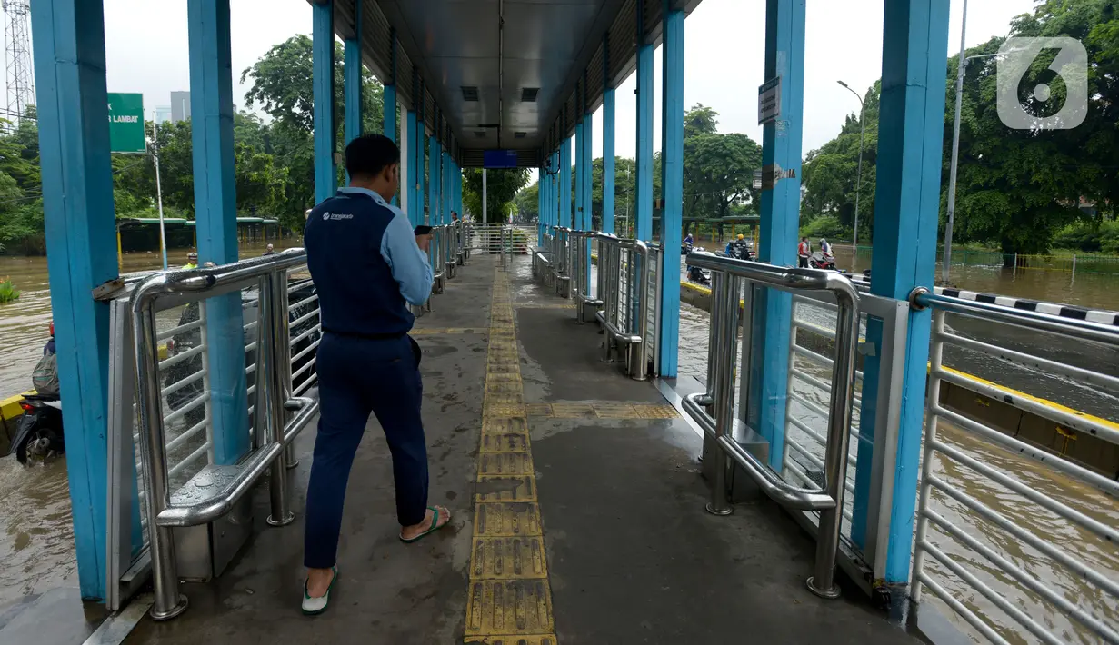 Petugas Transjakarta berjalan saat banjir merendam Jalan Letjen Suprapto, Jakarta, Pusat, Sabtu (8/2/2020). Hujan yang mengguyur Jakarta sejak semalam mengakibatkan Jalan Letjen Suprapto terendam banjir. (merdeka.com/Imam Buhori)