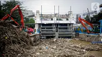 Petugas dibantu alat berat membersihkan sampah kayu dan bambu yang tersangkut di Pintu Air Manggarai, Jakarta, Rabu (9/10/2019). Sekitar 80 ton sampah sudah diangkut menggunakan alat berat. (Liputan6.com/Faizal Fanani)