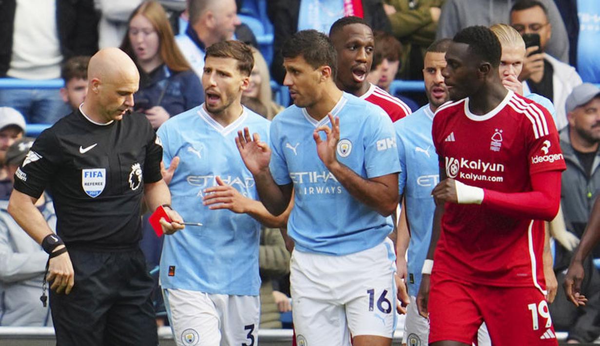 Pemain Manchester City, Rodri, berusaha menahan wasit untuk memberikan kartu merah saat melawan Nottingham Forest pada laga Liga Inggris di Stadion Etihad, Minggu (24/9/2023). (AP Photo/Jon Super)