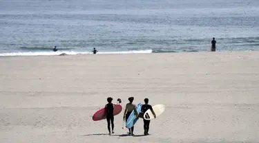 Orang-orang berjalan di pantai untuk berselancar di pantai Yotsukura, sekitar 30 kilometer (sekitar 18 mil) selatan pembangkit listrik tenaga nuklir Fukushima Daiichi, yang rusak akibat gempa bumi dan tsunami besar 11 Maret 2011, di Iwaki, timur laut Jepang, Sabtu, 26 Agustus 2023. (AP Photo/Eugene Hoshiko)