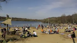 Orang-orang menikmati cuaca hangat di Ruislip Lido di London, Selasa (30/3/2021).  Suhu di beberapa bagian Inggris diperkirakan akan lebih hangat secara signifikan minggu ini karena keluarga dan teman berkumpul kembali dan kegiatan olahraga luar ruangan diizinkan untuk dilanjutkan di Inggris. (AP Ph