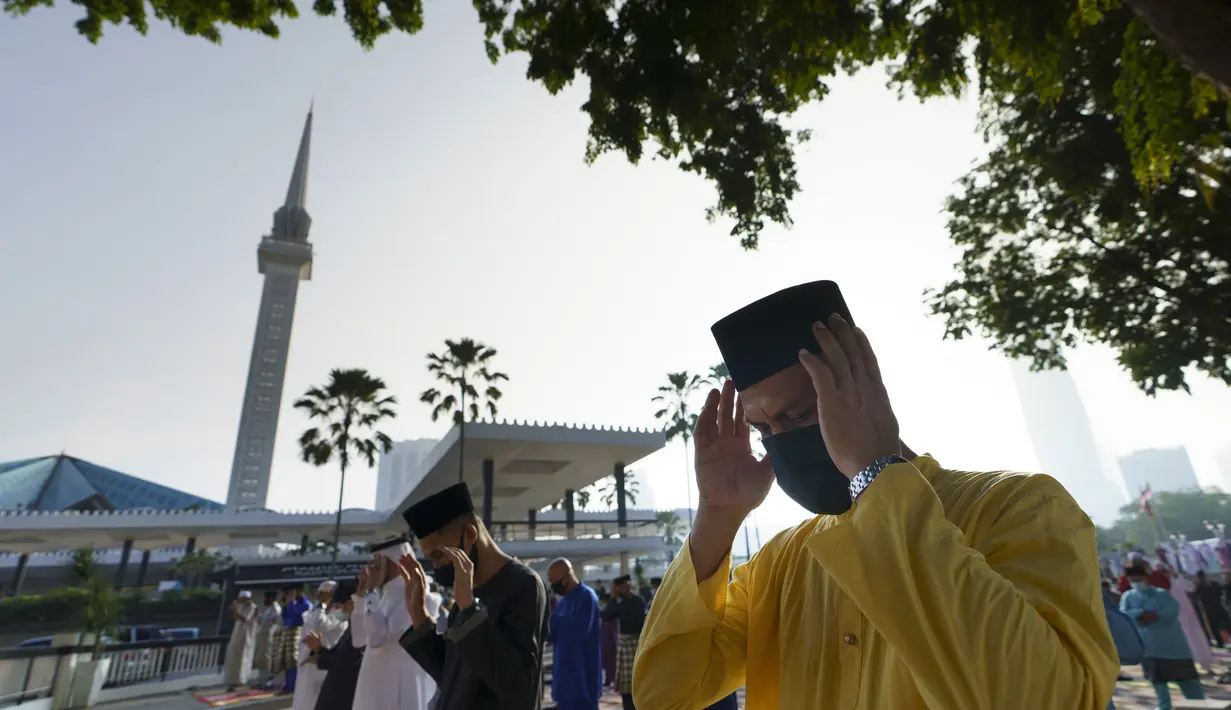 Umat Muslim yang mengenakan masker untuk meredam penyebaran wabah virus corona melaksanakan sholat Idul Fitri menandai akhir bulan suci Ramadhan di luar Masjid Nasional di Kuala Lumpur, Malaysia, Kamis (13/5/2021). (AP Photo/Vincent Thian)