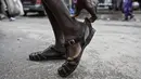 Seorang pria memakai sepatu Leke di Treichville, Abidjan, Pantai Gading pada 14 September 2023. Di Abidjan, musim hujan akan segera berakhir, tetapi orang-orang tidak pernah menyimpan "leke" mereka - sandal plastik yang murah dan kedap air, yang telah menjadi simbol identitas budaya Pantai Gading. (Sia KAMBOU / AFP)
