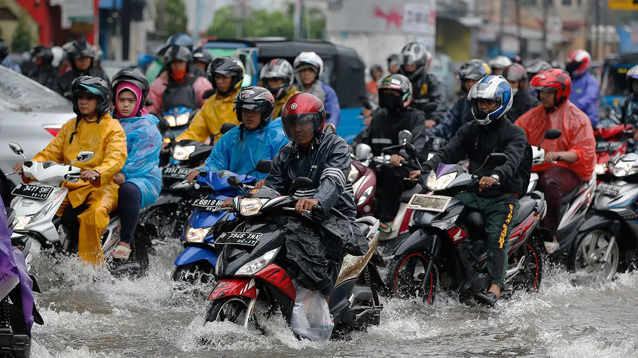 Pengendara sepeda motor melewati persimpangan yang banjir (Darren Whiteside)